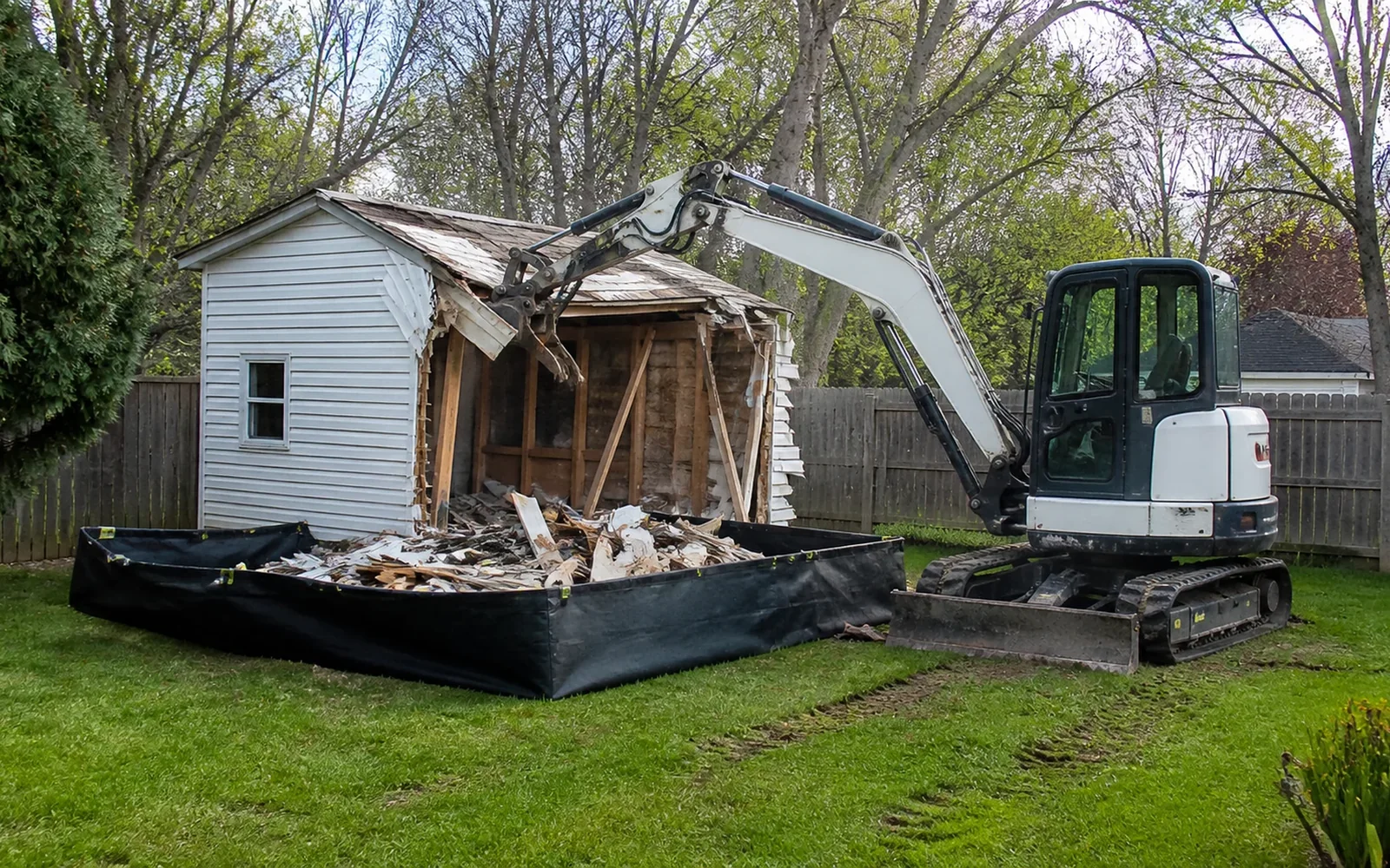 Small excavator performing controlled demolition at an unbranded Columbus job site